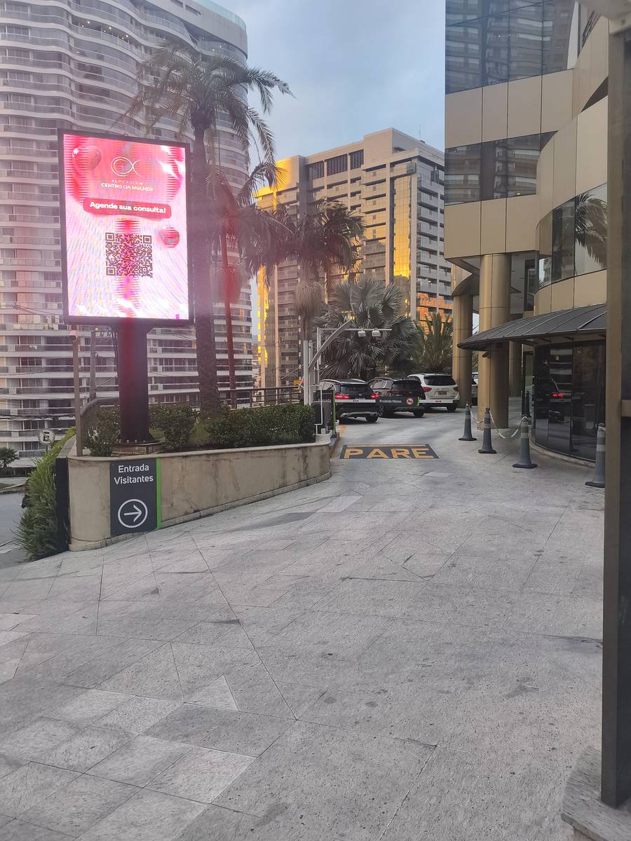 Rampa de acesso do edifício, com a placa indicando a entrada de visitantes