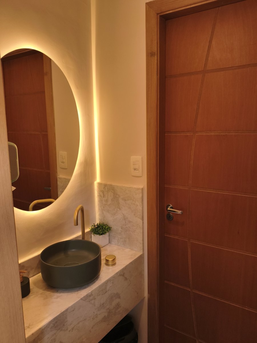 Lavabo da Clínica Gusman, com bancada de mármore, cuba preta e espelho redondo iluminado