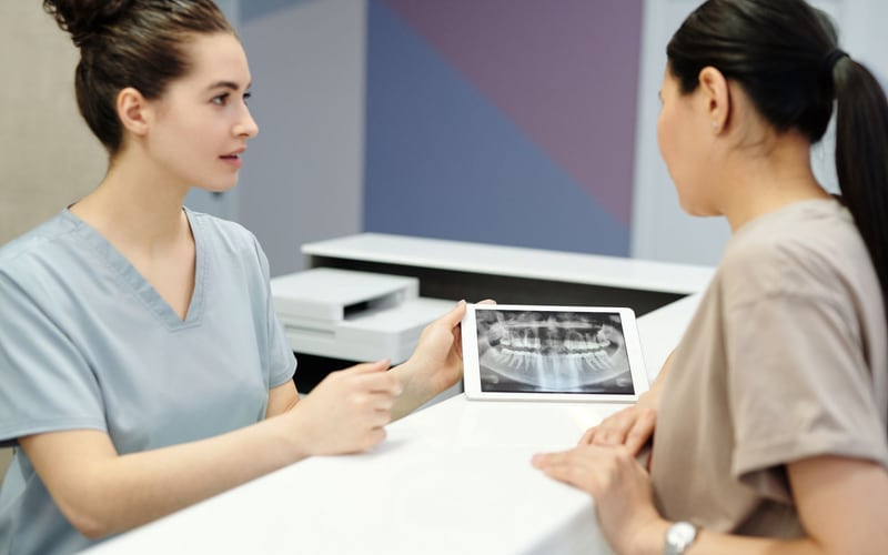 Dentista explicando uma radiografia panorâmica durante a consulta