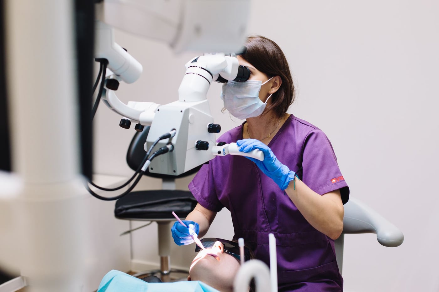 Dentista utilizando microscópio durante atendimento odontológico
