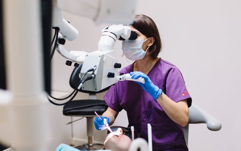 Dentista utilizando microscópio durante atendimento odontológico